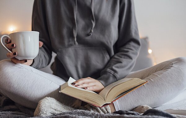 Mutter entspannt mit Buch und Tee