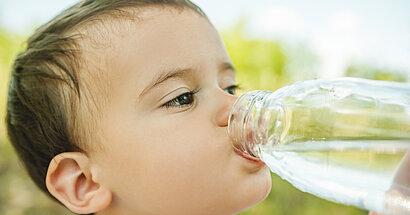 Kleinkind trinkt Wasser aus einer Flasche.