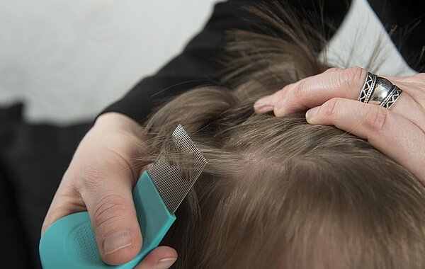 Mutter untersucht die Haare ihres Kindes auf Kopfläuse